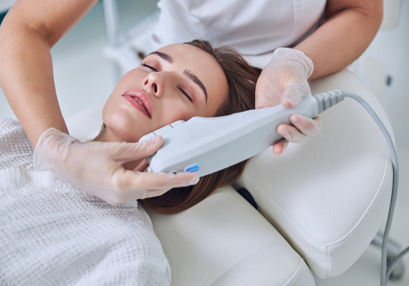 Beautiful young woman receiving professional non surgical face lifting in spa salon